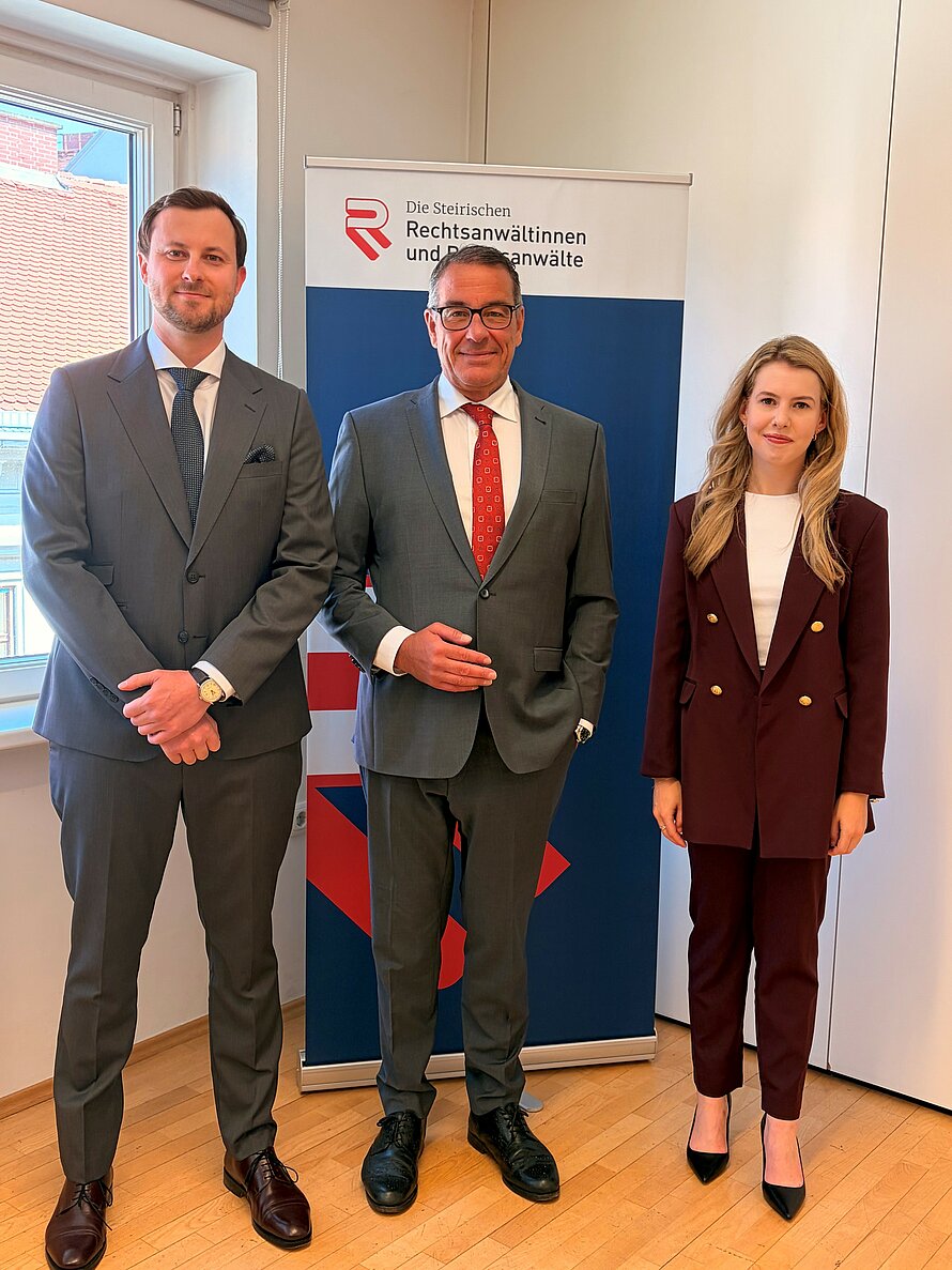RA Mag. Messerklinger links und RA Mag. Leitenbauer rechts stehen mit VP Mag. Dlaska vor dem Roll-up.